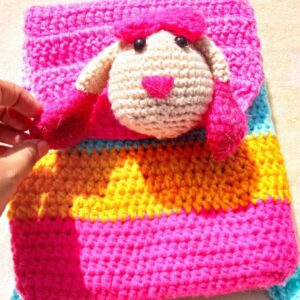 a hand holding a crocheted bunny backpack 